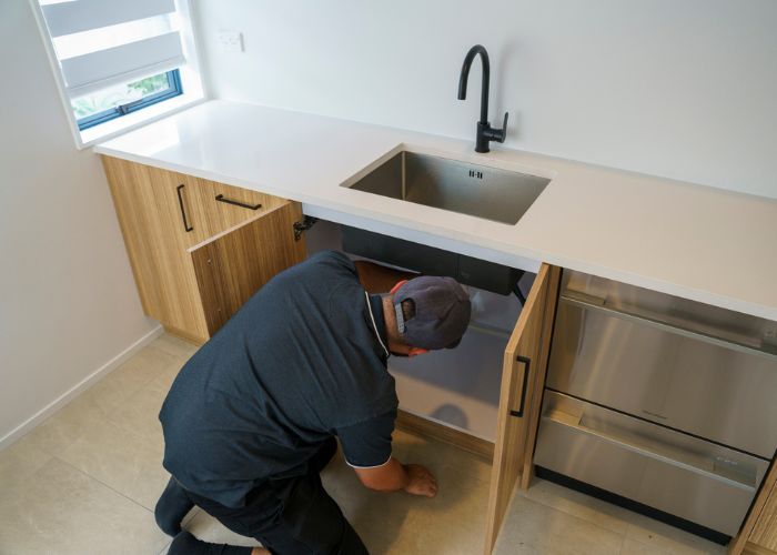 Auckland plumber inspecting under sink during pre-purchase inspection